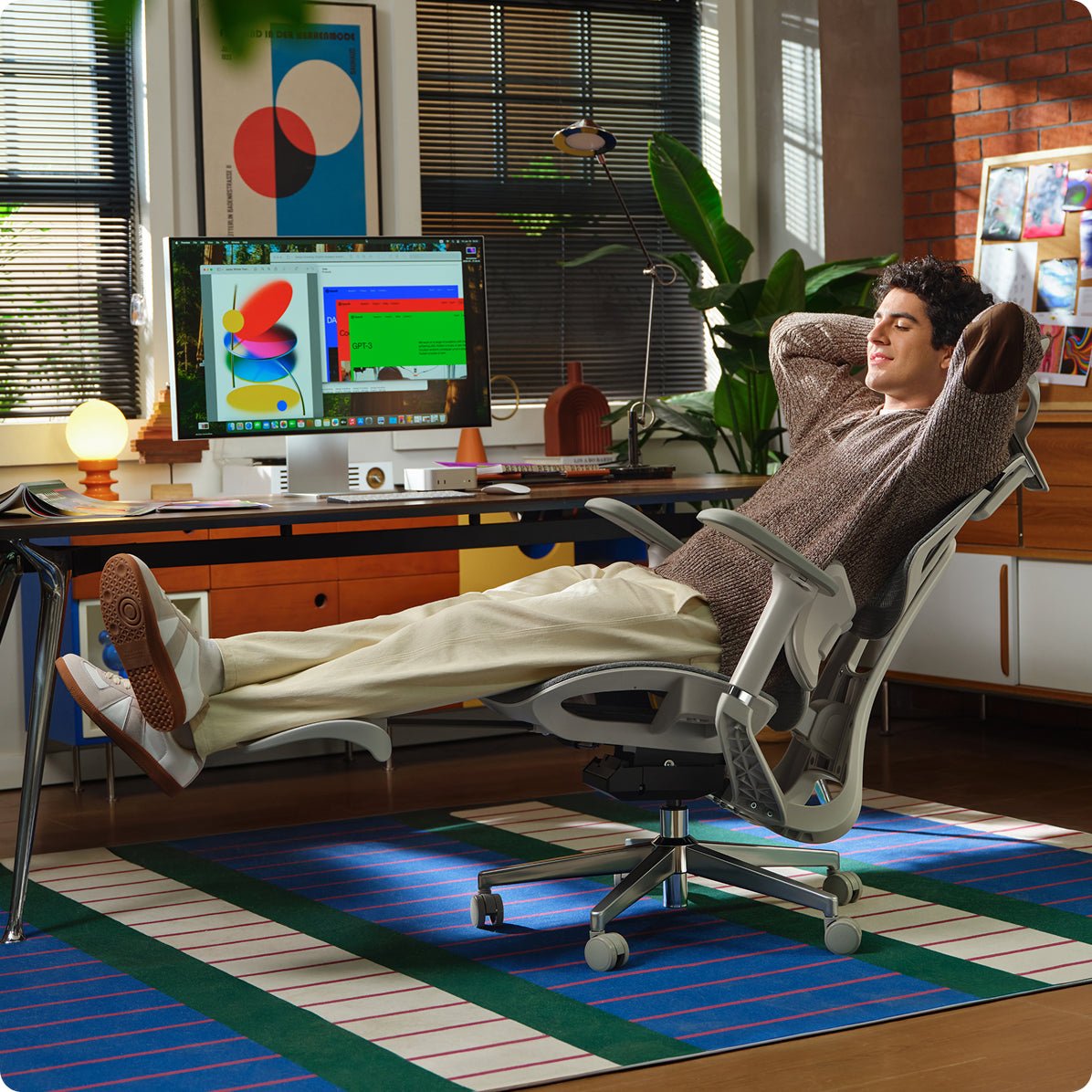 Person lounging in a modern office chair with a computer setup in the background ~scene